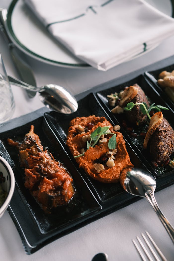 Close-up of gourmet appetizers on a black tray with spoons, perfect for food lovers.