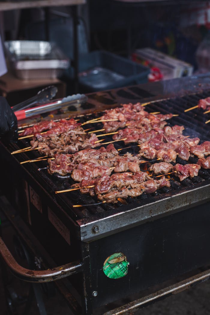 Offerings Close-up of deliciously grilled meat skewers sizzling on an outdoor barbecue grill.