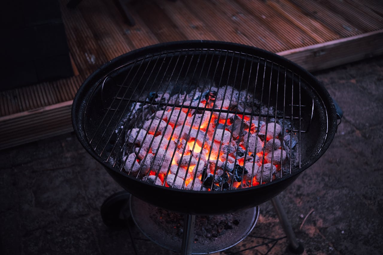 Offerings Close-up of glowing charcoal briquettes in a round outdoor grill, ready for barbecue cooking.