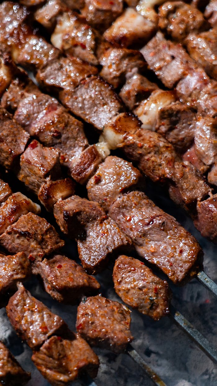 Offerings Close-up of deliciously grilled beef kebabs on skewers with a smoky background.